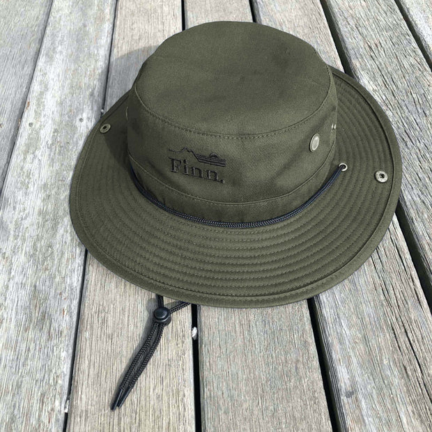 Squad Green Out There Brim Hat lying on decking.