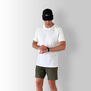 Front angled view of model wearing a white Out There Organic Tee in studio.